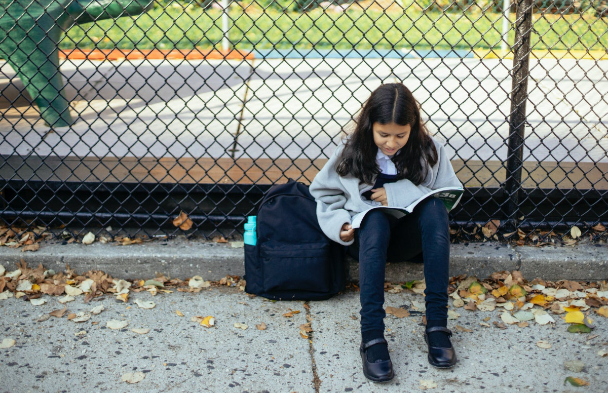 focused girl reading textbook on street