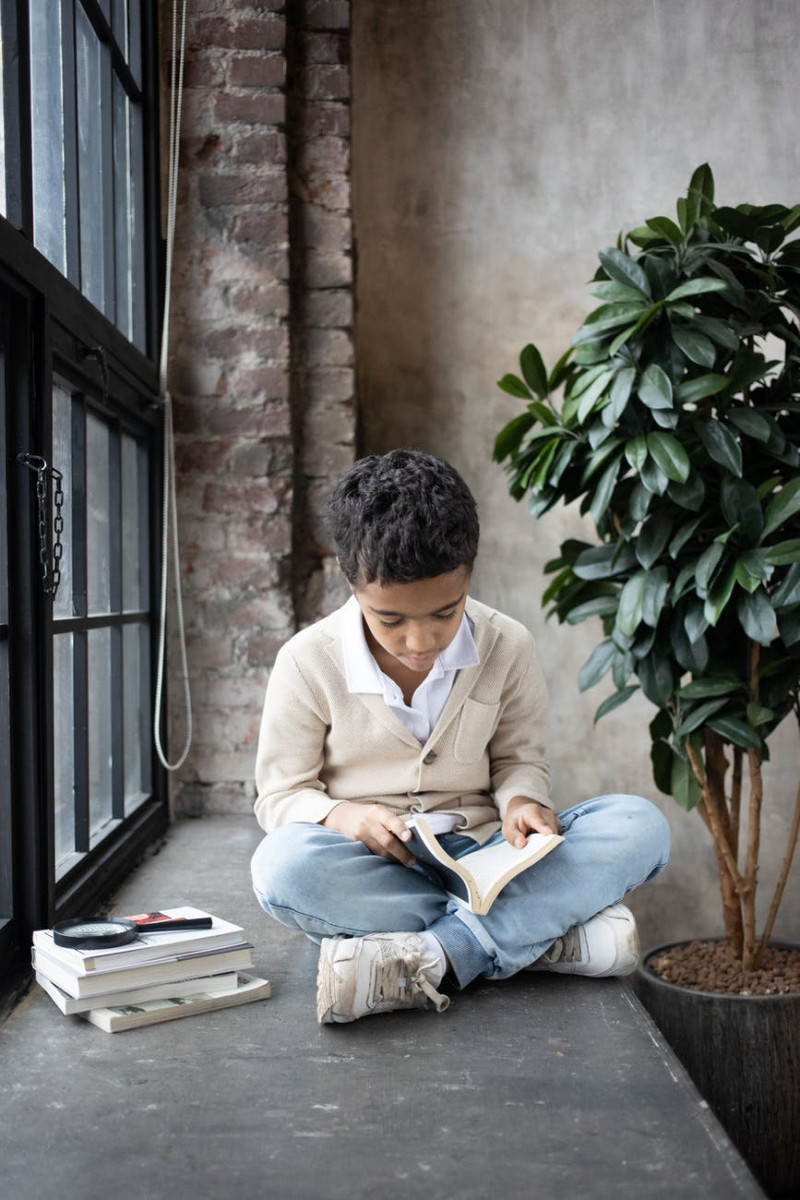 concentrated arabian child reading interesting book while sitting near window