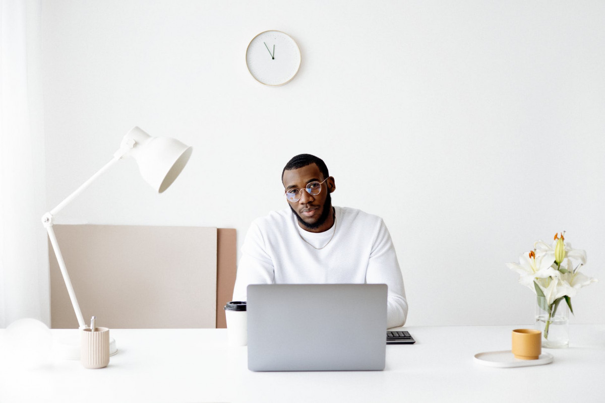 photo of man wearing white sweater in front of laptop