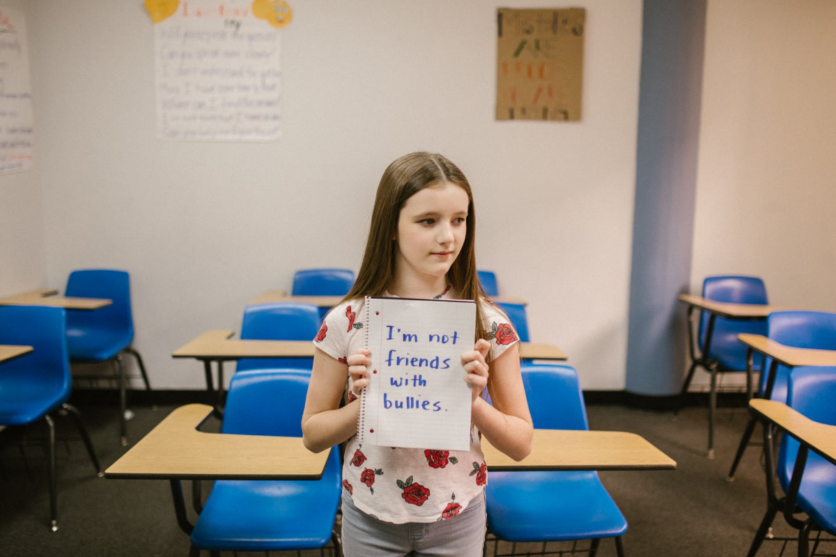 girl showing a message against bullying written in a notebook