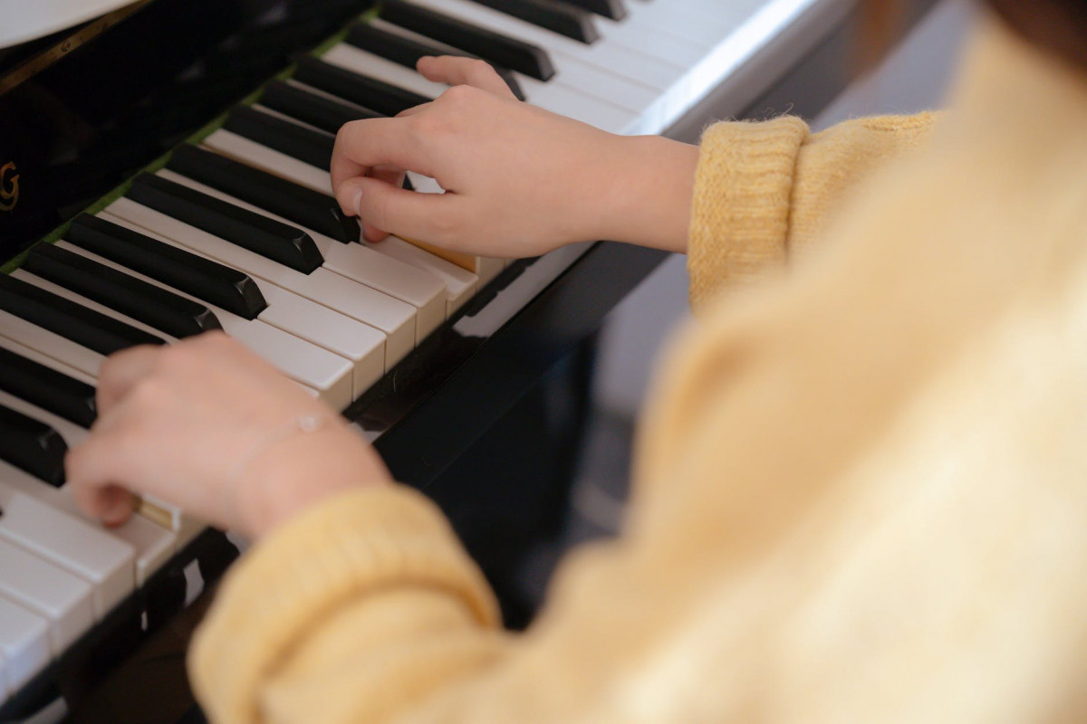 woman in yellow sweater playing piano