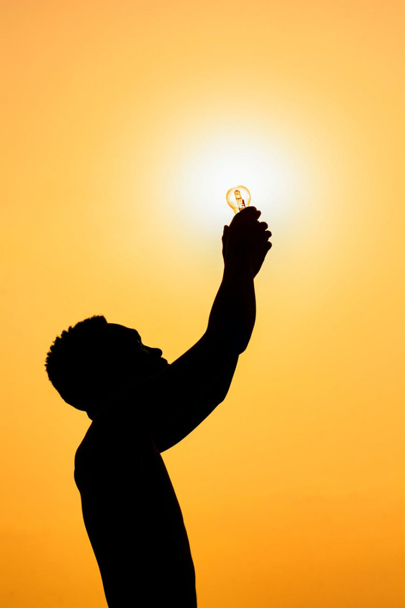 silhouette of man with light bulb at sundown